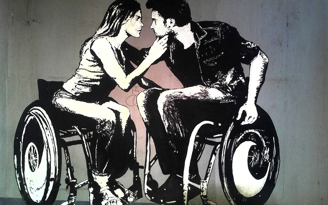 A desaturated image of a man and woman, each in a wheelchair, embracing.