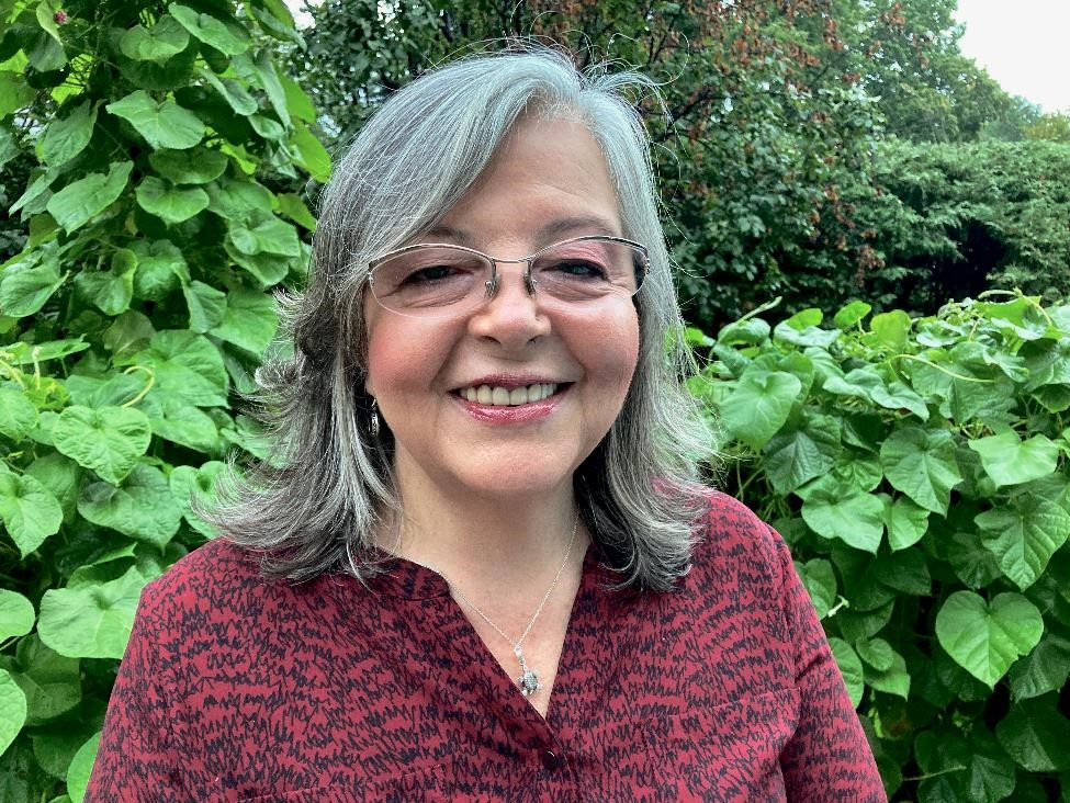 Headshot of Yolanda Munoz, smiling with green leaves in the background.