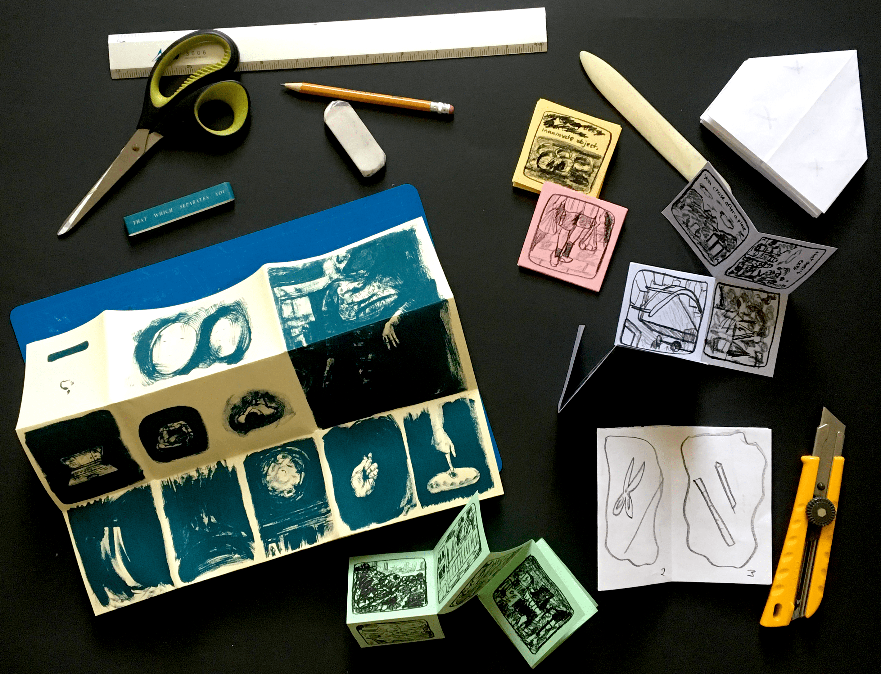collection of colourful zines with scissors, a pencil, and an exacto knife on a black background
