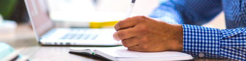 man in blue shirt writing on a paper