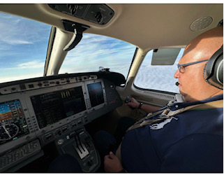Man in cockpit of a plane flying above the clouds