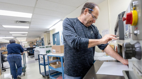 Man working with a big machine to cut print jobs