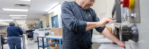 Man working with a big machine to cut a printing job