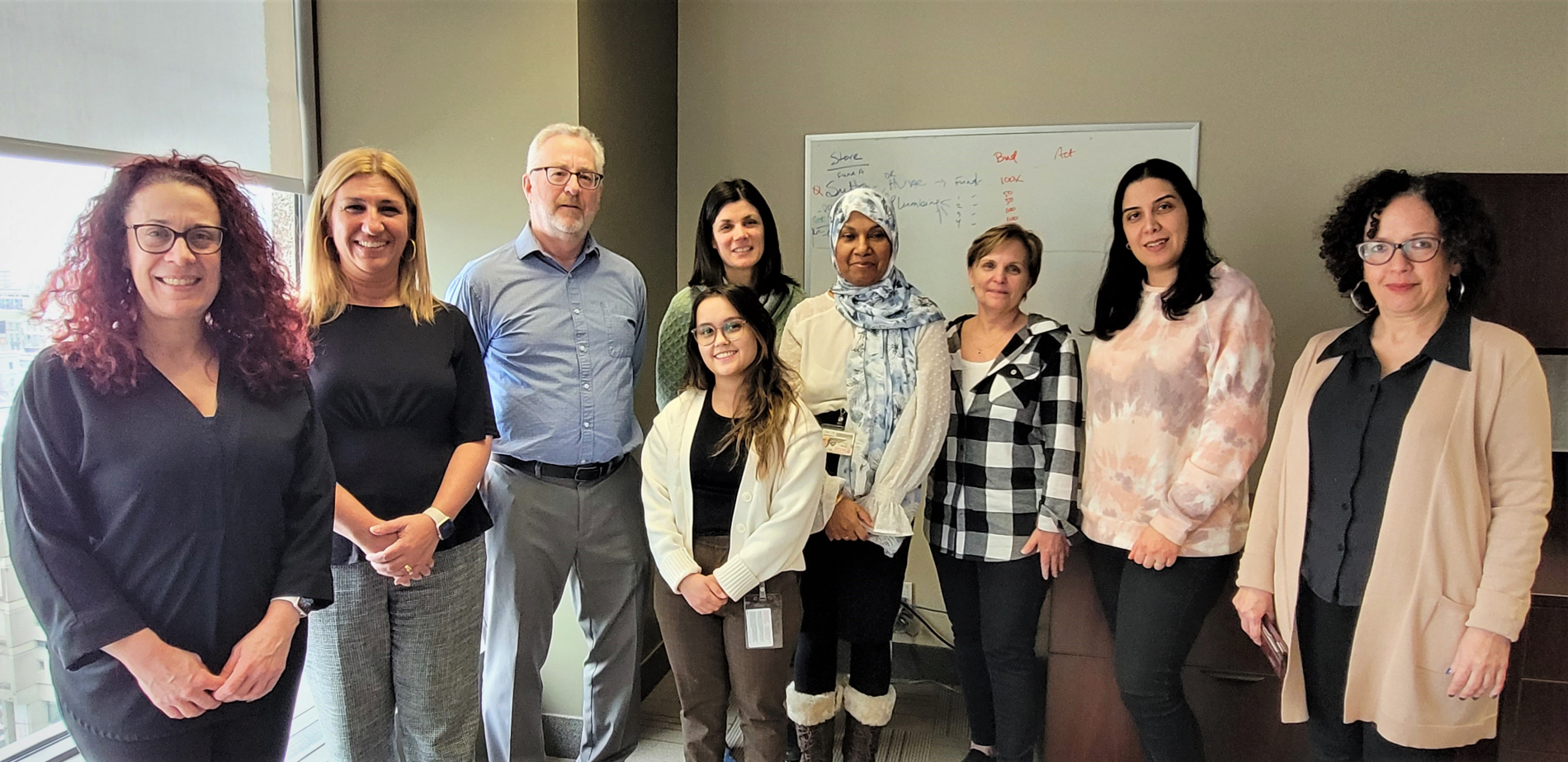 The FSFM team. Eight women and one man stand next to each other in an office and smile to the camera.