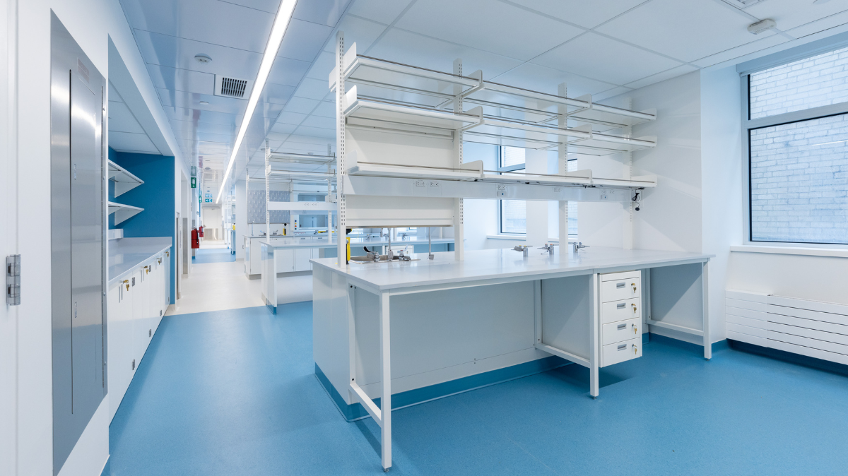 Wet lab at the Lyman Duff Building as part of the new hub for pain research. Empty lab with white desks, shelves, and cabinets and a bright blue floor.