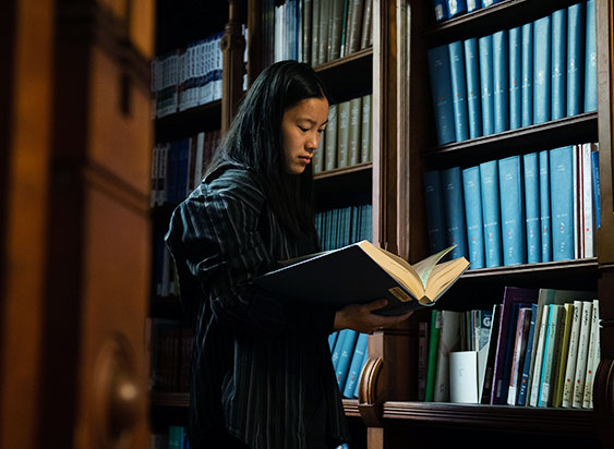 Woman reads book in library 