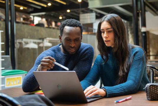 Two students sitting in front of laptop on desk