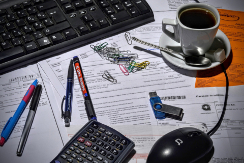 Desk with papers, pens, computer, mouse, coffee