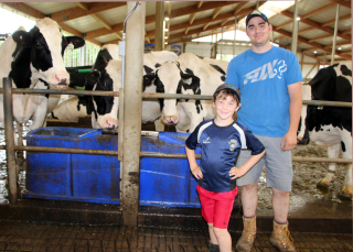 student Jeremy Chevalley and a child stand in front of dairy cows at Ferme Nieuwenhof et associés in Ste-Agnes-de-Dundee, QC.