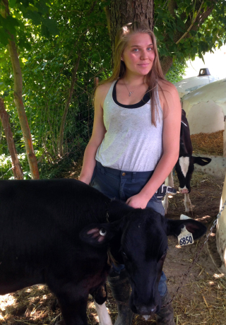 FMT student stands with dairy calf during her summer internships for the program