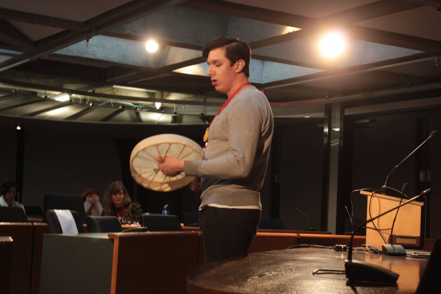 Student playing hand drum and singing for conference audience