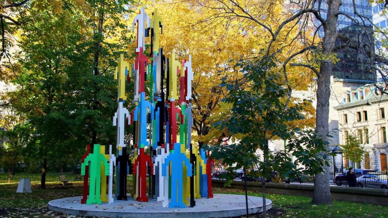 Human Structures statue by Jonathan Borofsky, a large metal structure composed of many multicolored human shapes stacked on top of each other