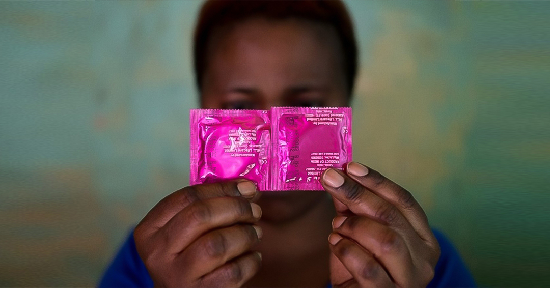A sex worker conceals her face with a pack of condoms in the Katosi fishing village in Mukono, located east of Kampala.