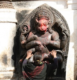 woman kneeling in front of a statue of a deity