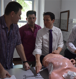 Surgery resident explaining a procedure to colleagues in front of a mannequin