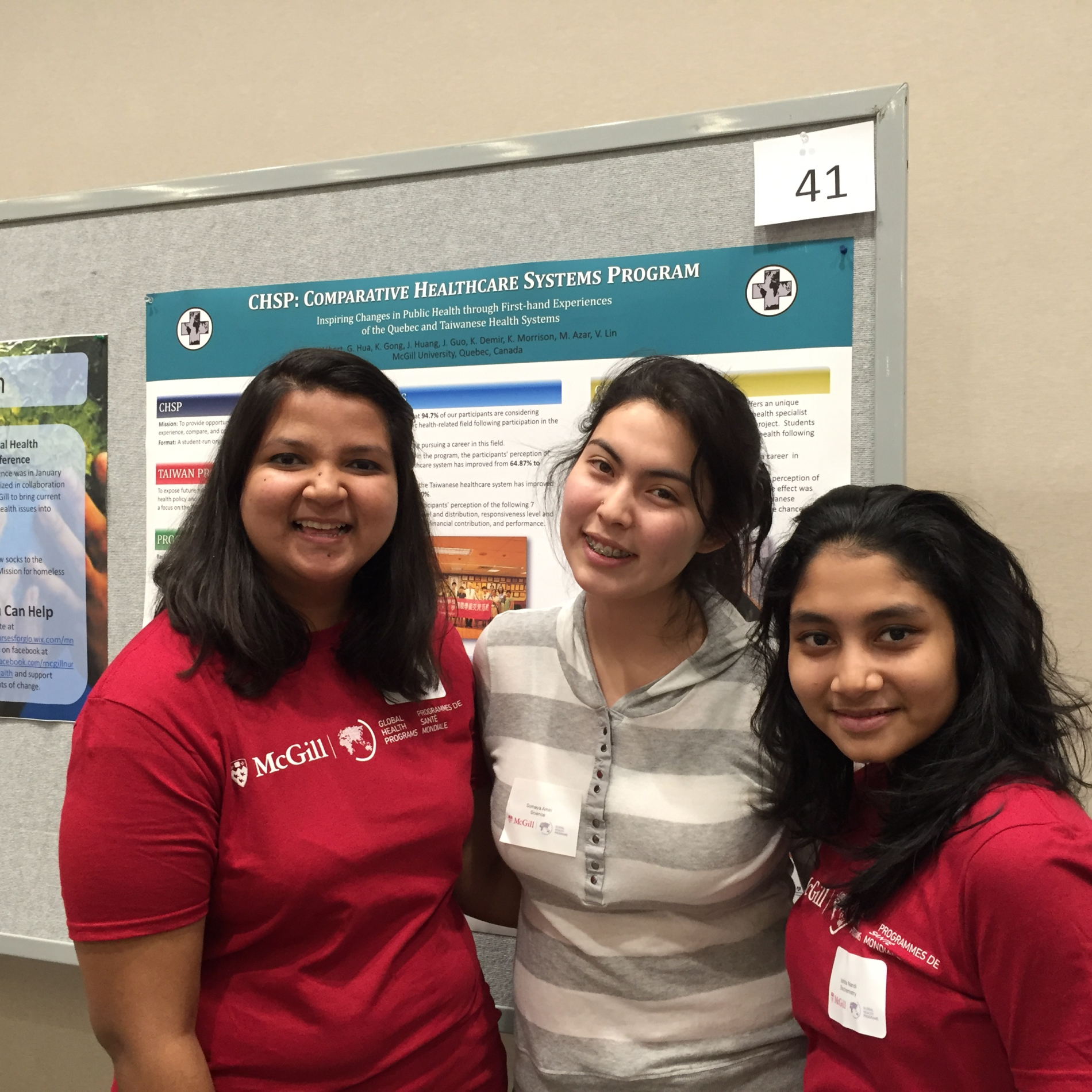 Three students pose in front of a poster at Global Health Night