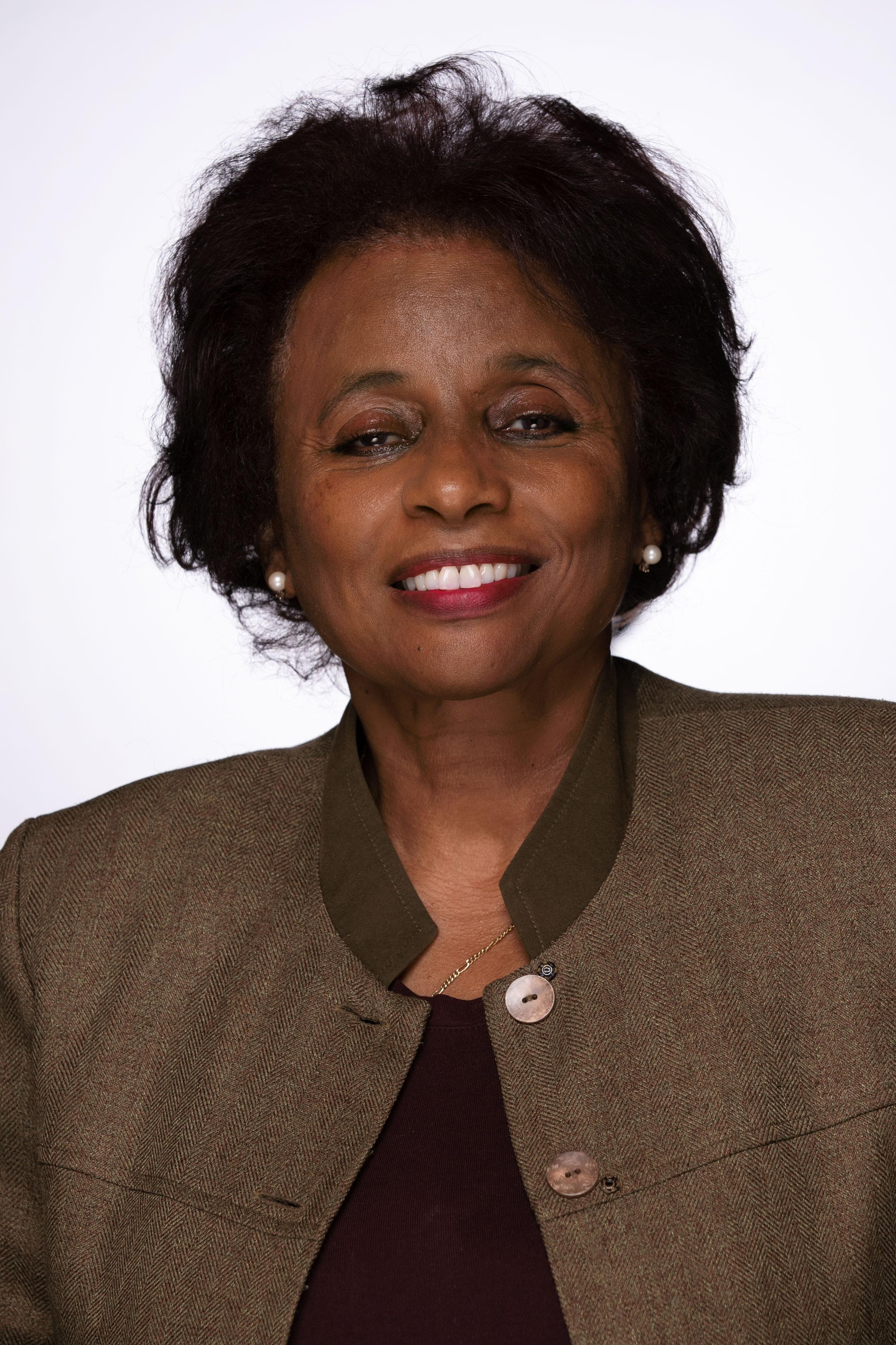 Portrait of Global Health Night 2022 keynote speaker Teguest Guerma - black woman wearing pearl earring and a brown shirt and jacket