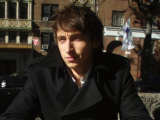 a young man looks in to far away. He is wearing a dark coat.