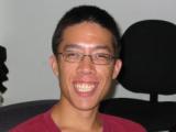 Young man with a huge smile. Short dark hair, glasses, friendly face