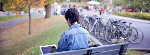man on park bench using a laptop