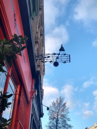 An overhead metal sign in the shape of a stave with notes and musical notations