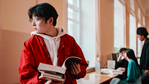 Student with books with other students in the background, photo by Yan Krukov