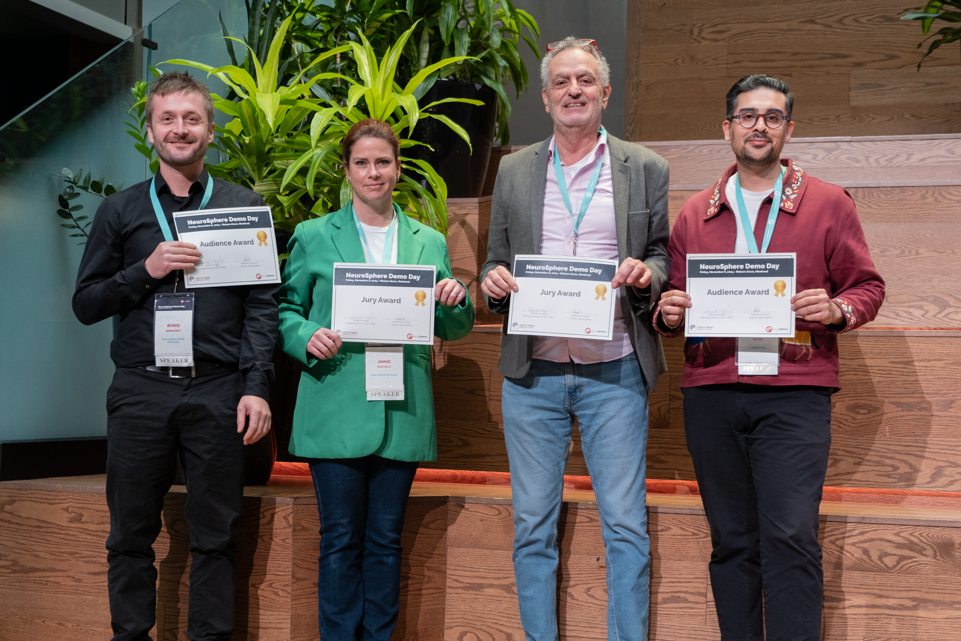 Demo Day winners holding up certificates on stage, smiling 