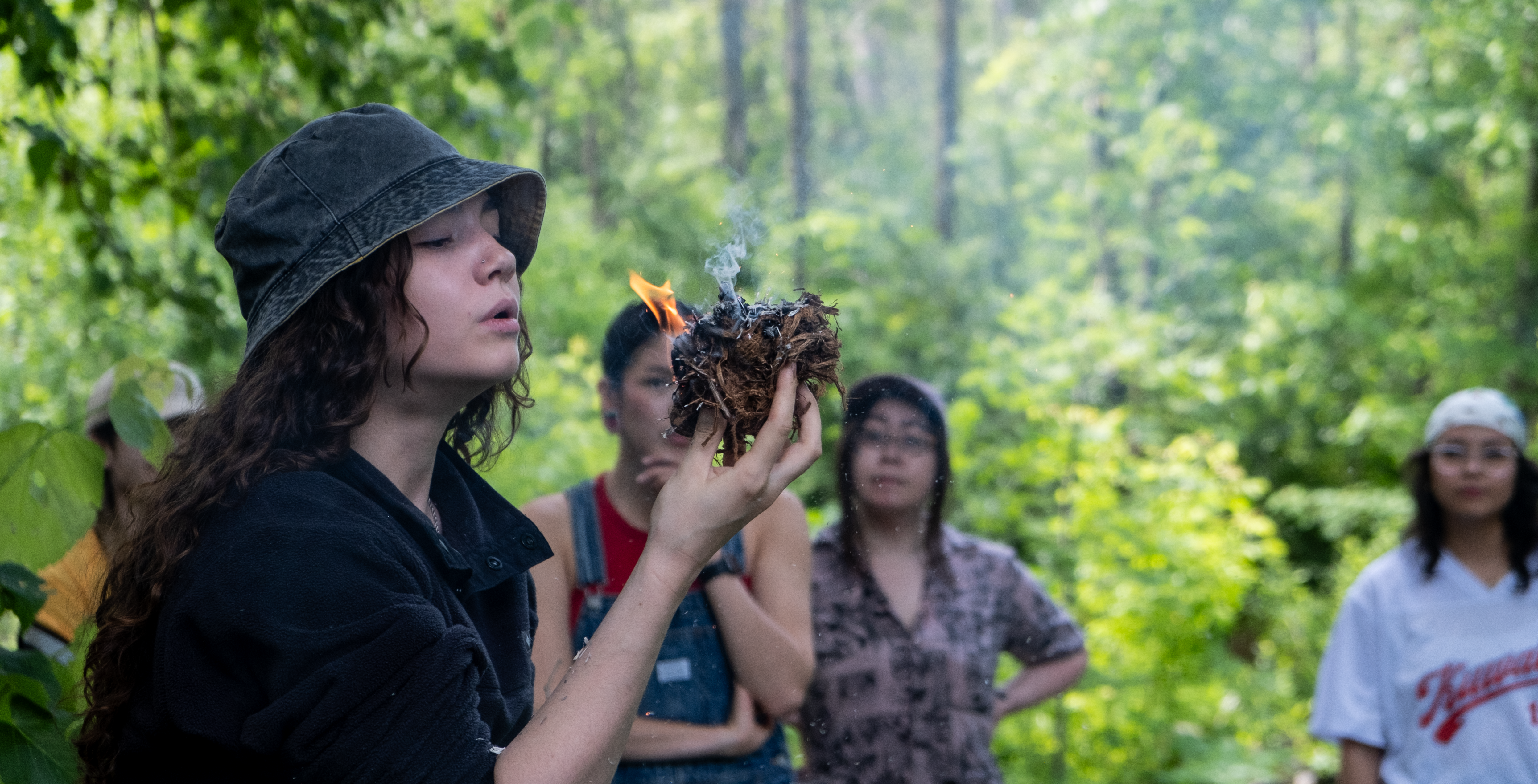 Student blows on fire at wilderness training skills day