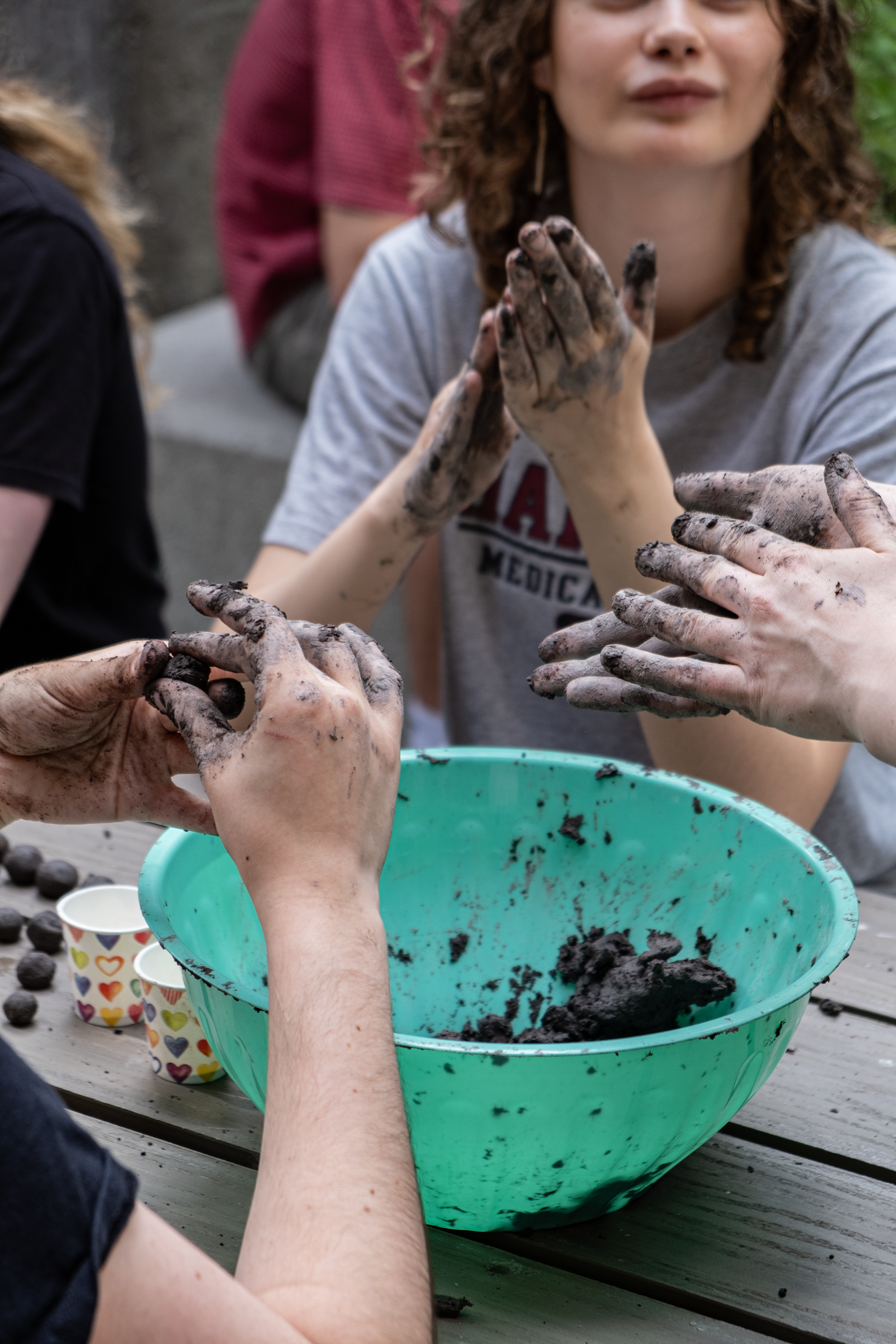 IMPRESS students at a gardening workshop, with hands covered in soil and working soil into balls
