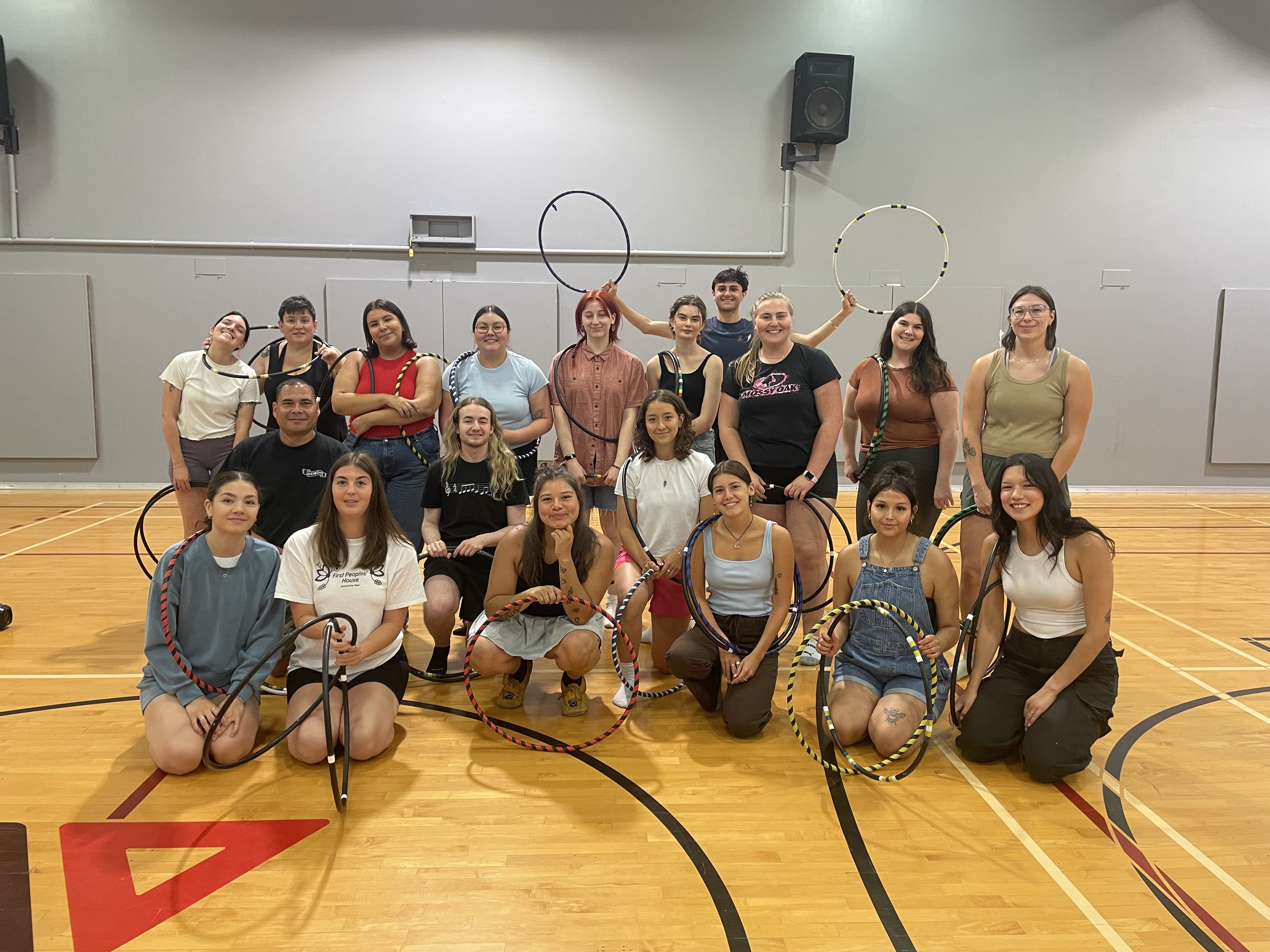 IMPRESS students at a hoop dancing workshop holding up hoops enthusiastically