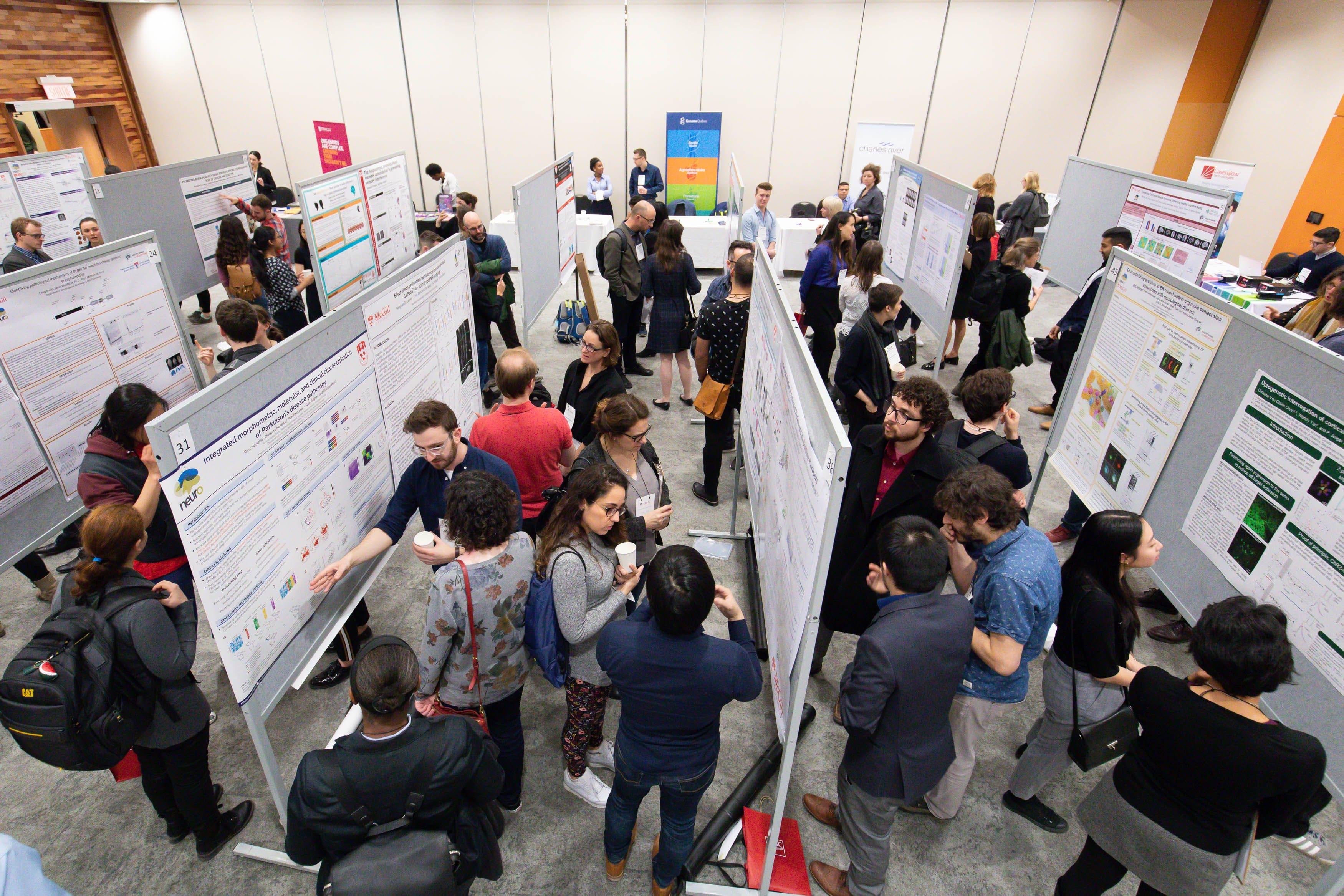 Event attendees at a poster session in a large hall, overhead view