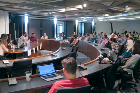 A panel discussion in a conference room full of attendees.