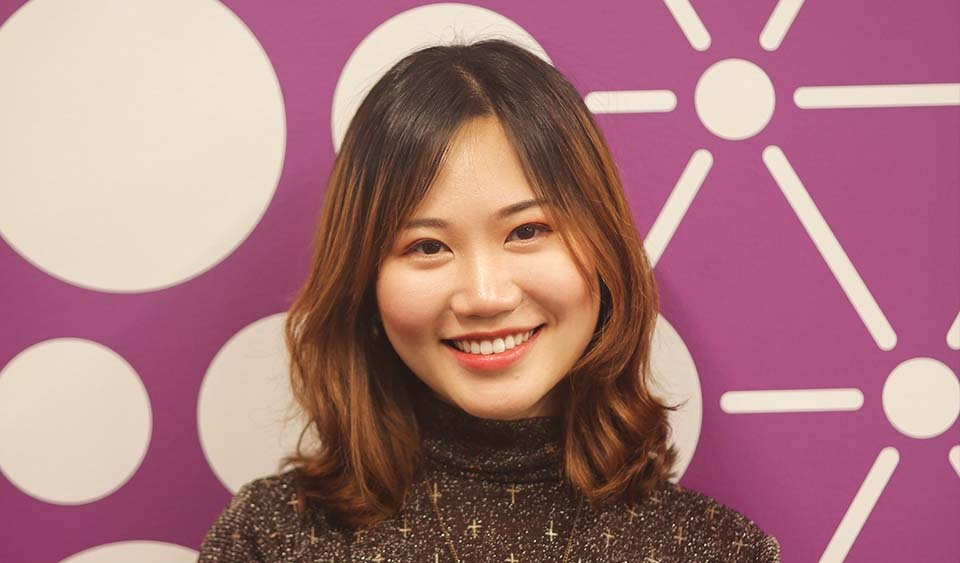 Professional headshot of Dongyan Lin in front of an abstract patterned purple background