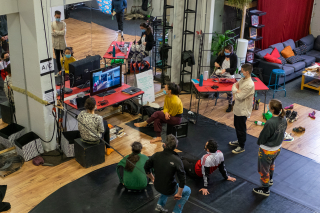 Piece of Mind Collective members grouped together on the floor of a dance studio take part in a video call