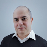 Professional headshot of Yashar Zeighami on grey background