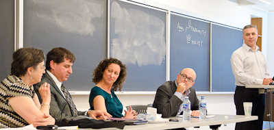 Panelists in conversation, with professor Gold watching.
