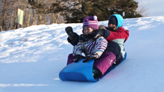 deux enfants glissant sur une pente en hiver