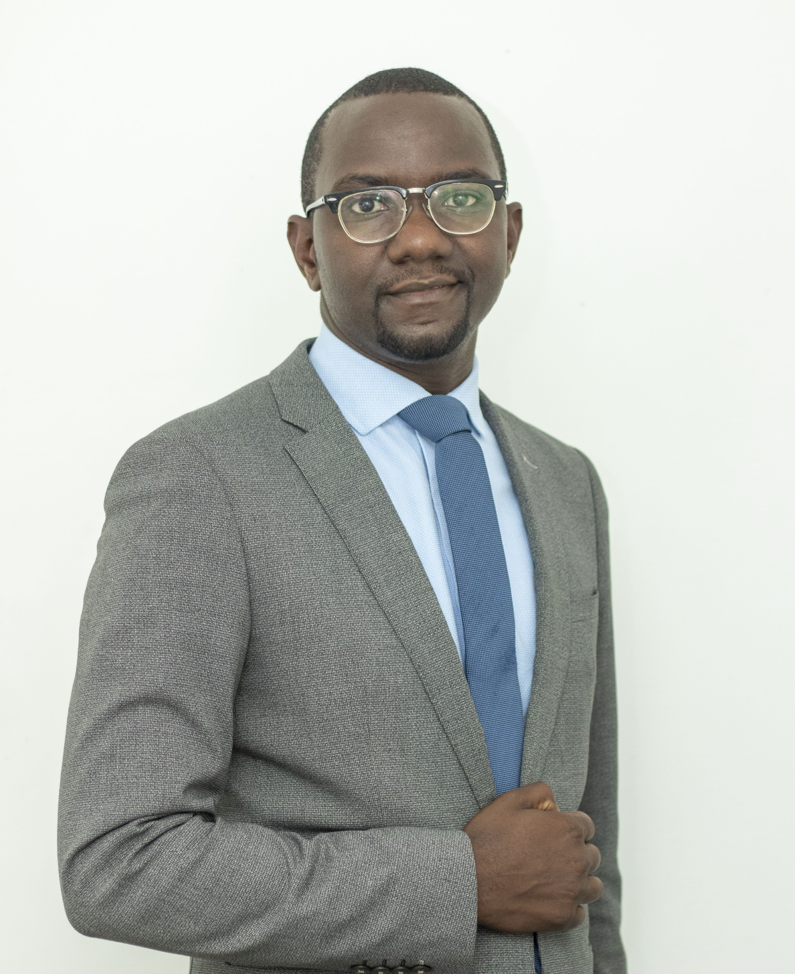 A Black man wearing a grey blazer with a blue tie