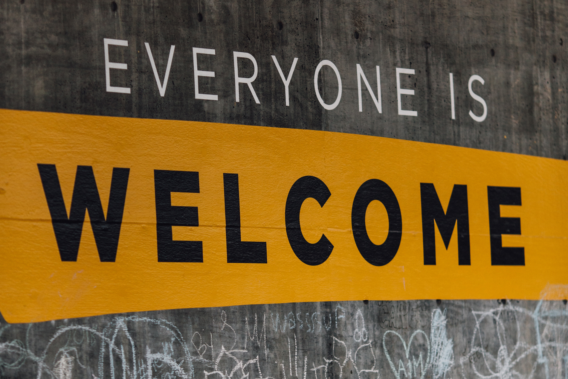 Sign on wall: Everyone is welcome (Credit: Katy Moum, Unsplash. Cropped from original)