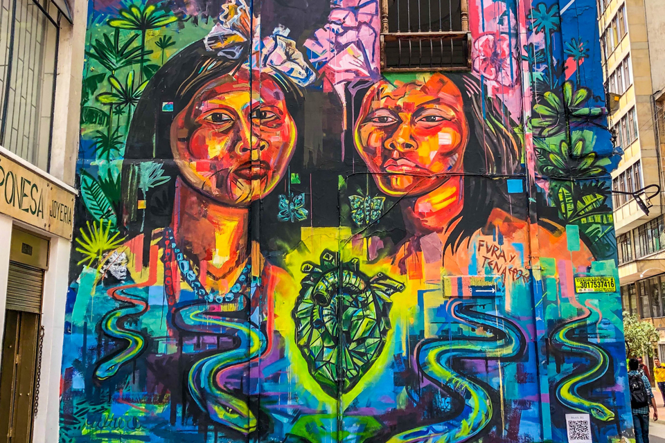 Detail of a colourful mural in Bogotá, Colombia, showing two stylized women and a glowing green heart between them. Credit: Jorge Gardner, Unsplash.com