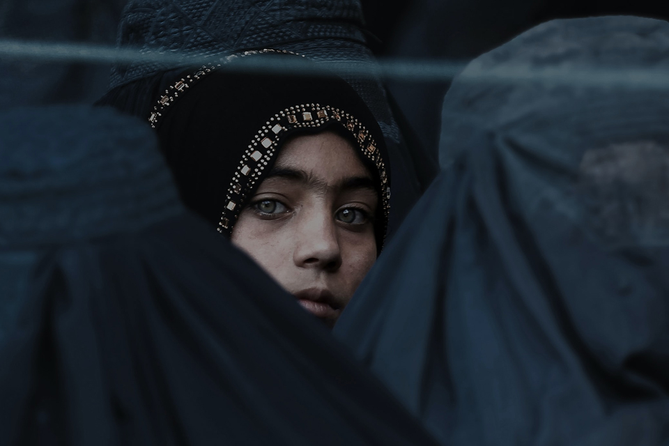 A young Afghan woman peers at the camera as her group lines up for relief assistance during the month of Ramadan in Jalalabad, Afghanistan. Photo by IsaaK Alexandre KaRslian, via Unsplash.com.