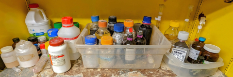 Yellow cabinet with multiple bottles with waste chemicals