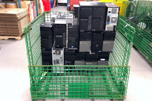 Green metal crate filled with old desktops that will be shipped to recycle. 