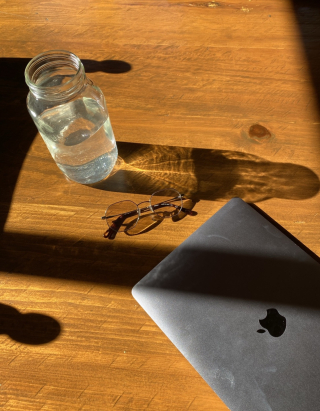 A computer and a glass of water, sunlight