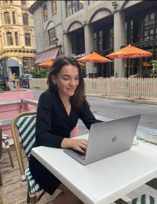 Meghan sitting at a terrace outdoors, working
