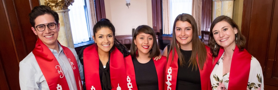 A row of smiling students with red sashes. 