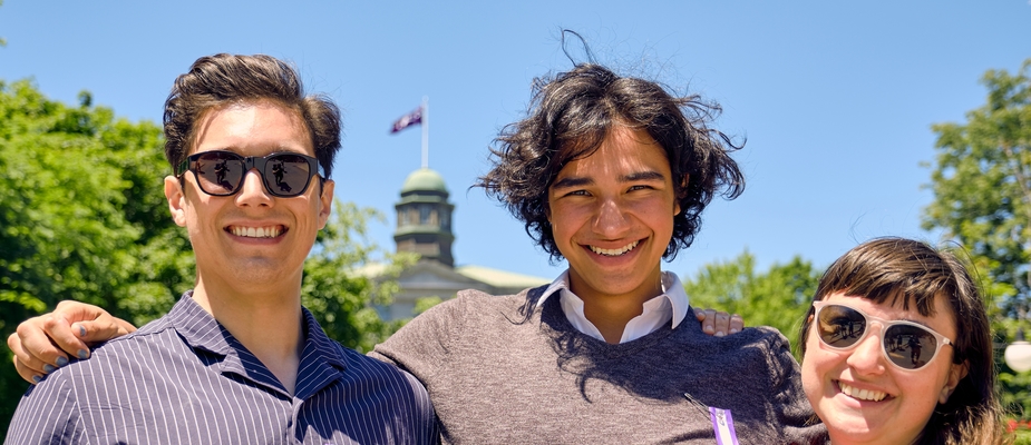 Three smiling Indigenous students on McGill campus, with trees and a domed roof in the background