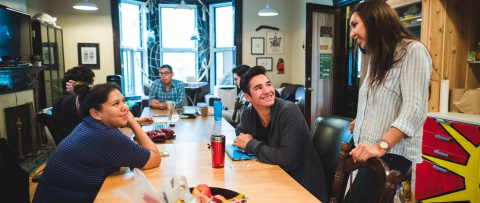 Des étudiants souriants sont assis ensemble à une table dans la Maison des Premiers Peuples