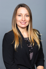 Portrait of Crystal facing the camera against a blueish-grey background.