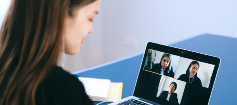 girl looking at laptop displaying 3 others in a virtual meeting